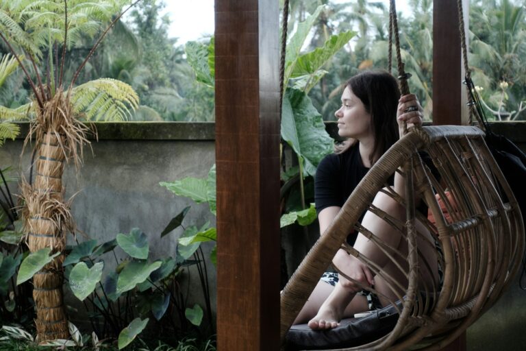 Woman relaxing in hanging chair with lush greenery background