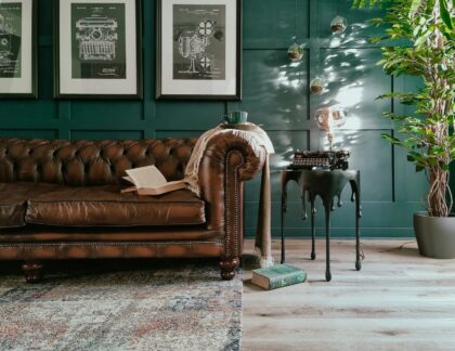 a living room with a brown leather couch and a potted plant